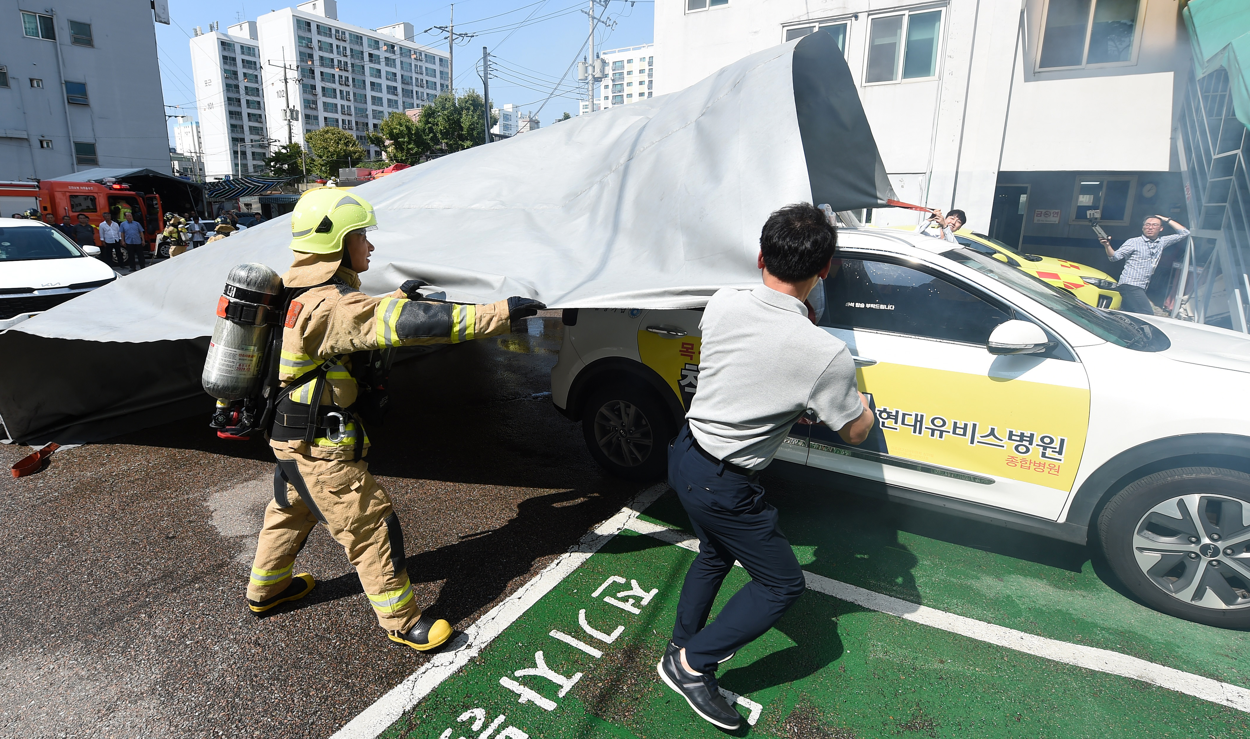 9일 미추홀구 삼정기업에서 열린 '전기택시 화재 대응 민·관 합동 훈련'에서 질식소화덮개를 이용해 화재진압을 하고 있다.